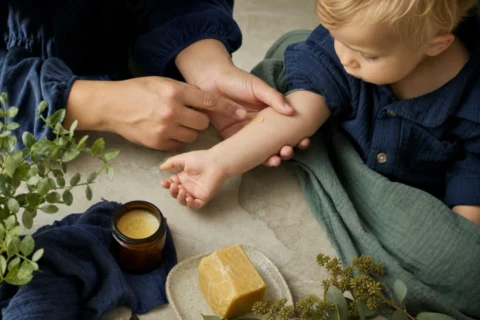 Caregiver applies a small dab of beeswax balm to a toddler's forearm.