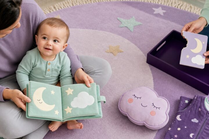 A baby sits with a mint cloth book while another caregiver holds a torn purple board book over a plum tray.