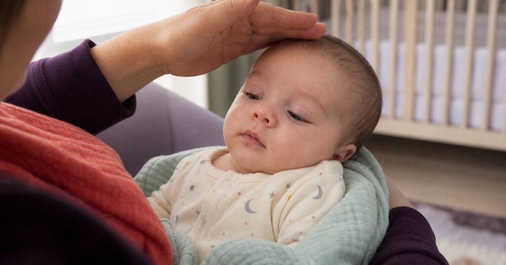 Caregiver gently shading the light while looking at a calm baby's faintly veined eyelids