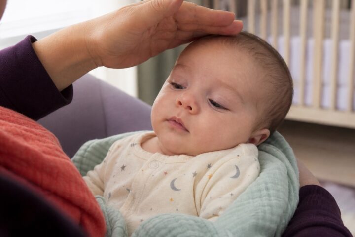 Caregiver gently shading the light while looking at a calm baby's faintly veined eyelids