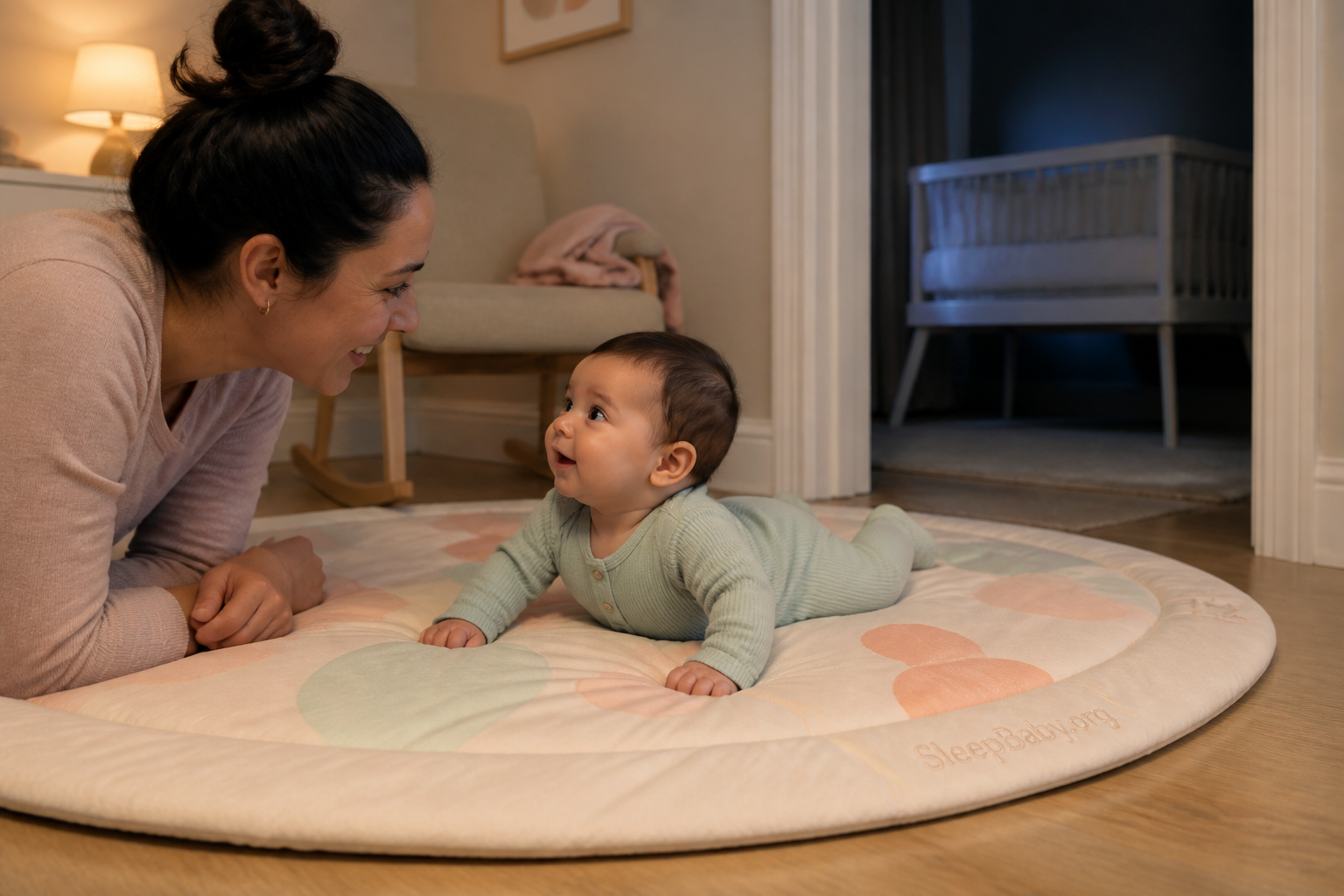 A wide-awake baby lifts their head during supervised tummy time with an empty bassinet visible beyond